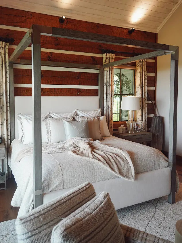 Metal canopy bed with white upholstered frame in rustic log cabin bedroom.